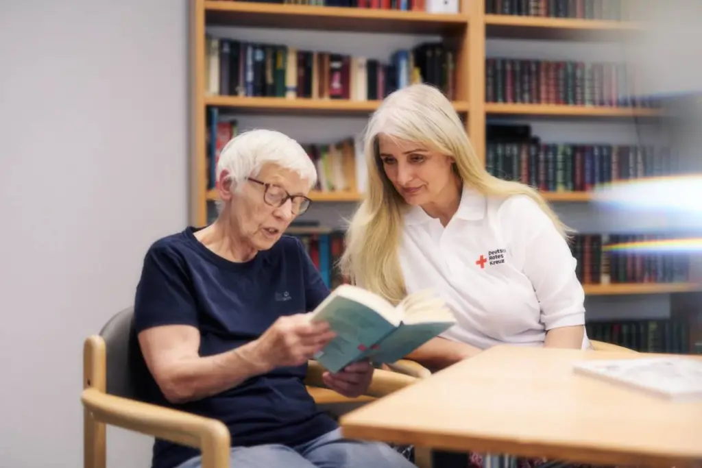 Pflegerin ließt ein Buch mit einer Patientin